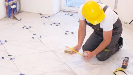 a master tiler measures dimensions with a tape measure while laying ceramic tiles on the floor