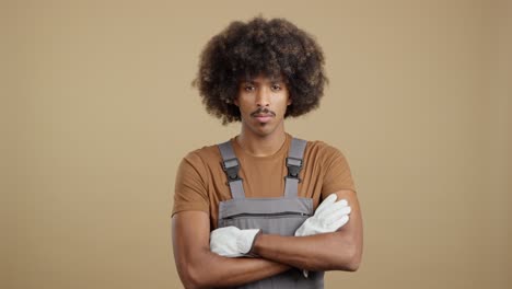 man with afro and mustache in work overalls and gloves with crossed arms