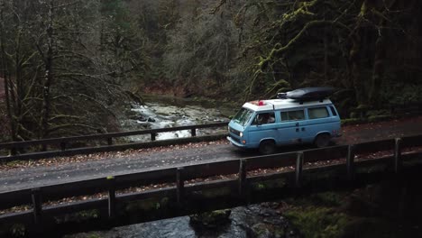 aerial shot of a volkswagen vanagon driving across a bridge in the pacific north west