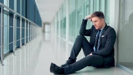 pretty man in business suit sitting on floor in despair