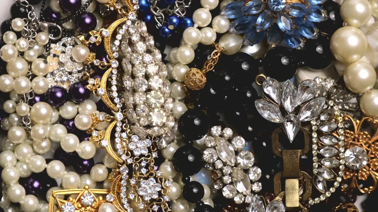 conjunto de joyas, fondo de rotación de oro amarillo y blanco. muchas hermosas joyas de moda femeninas con piedras preciosas brillantes, perlas y diamantes para mujeres. riqueza y concepto de lujo, primer plano, macro