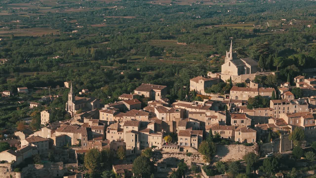 Aerial descending pan up to establish Bonnieux, Provence, France, highlighting the village’s scenic rooftops and historic buildings rising above lowlands