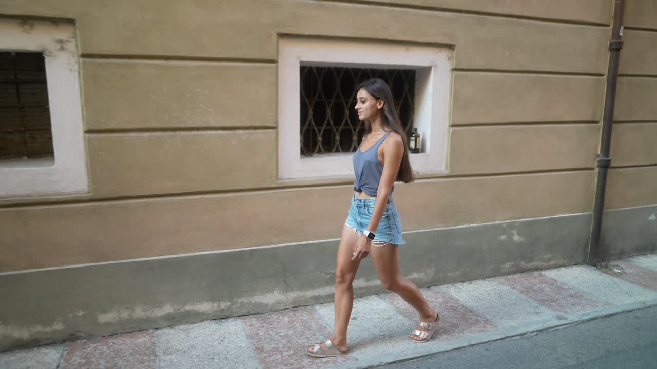 Giovane donna che cammina per una strada di città italiana