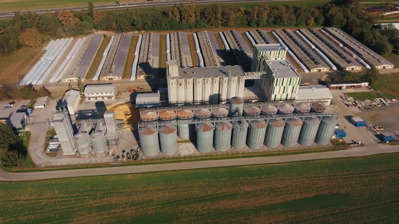 Eine Luftaufnahme zeigt Getreidesilos in einer landwirtschaftlichen Lageranlage, umgeben von Feldern. Lastwagen sind
