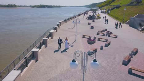 happy couple walks along modern waterfront bird eye view