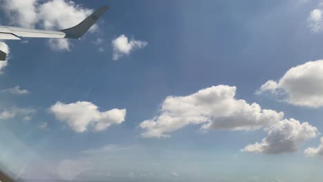 Airplane-wing-seen-from-the-window-while-in-flight-on-a-sunny-afternoon