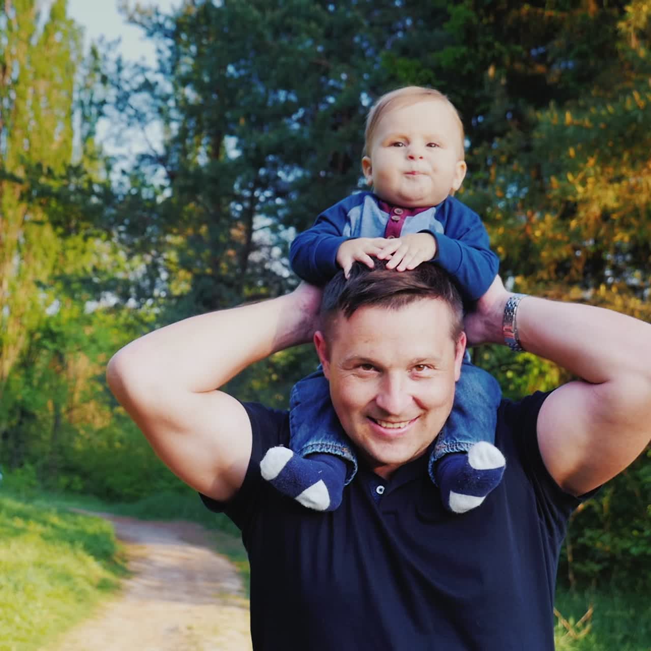 A Young Healthy Father Carries His Son On His Shoulders 1