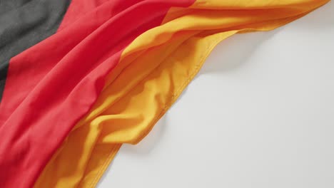 Video-of-creased-flag-of-germany-lying-on-white-background