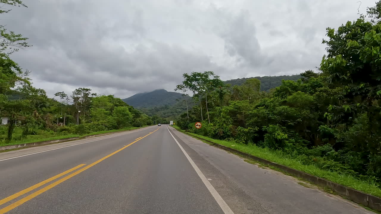 Drivers POV shot of driving through roads of Brazil during daytime. Mountains at background.