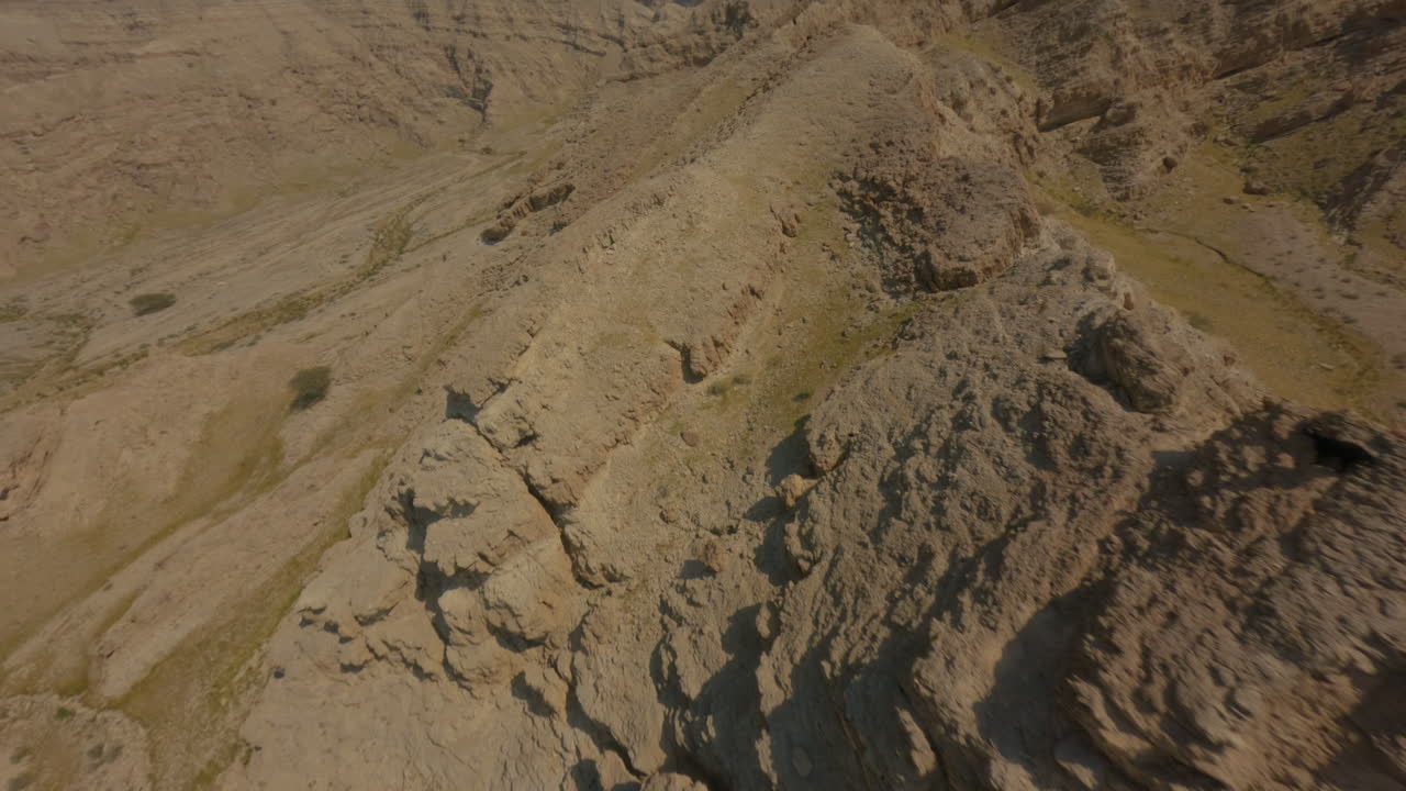 FPV drone flies over the rocky terrain of Hatta Desert, climbing along the ridge and swaying side to side before continuing its fast ascent