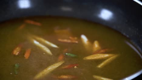 adding chilli lemongras and galangal in traditional thai tom yum soup