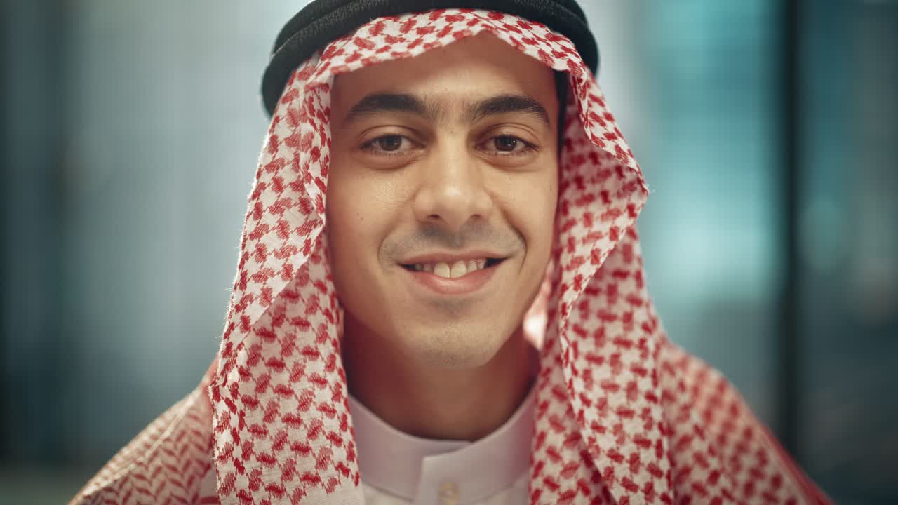 retrato de un joven empresario árabe exitoso en traje tradicional sonriendo suavemente, con kandura blanca y agal negro manteniendo un ghutra en su lugar. concepto de empresario árabe saudí, emiratí.