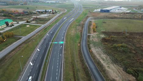 A-dual-lane-road-in-an-autumn-field,-with-cars-driving-on-it