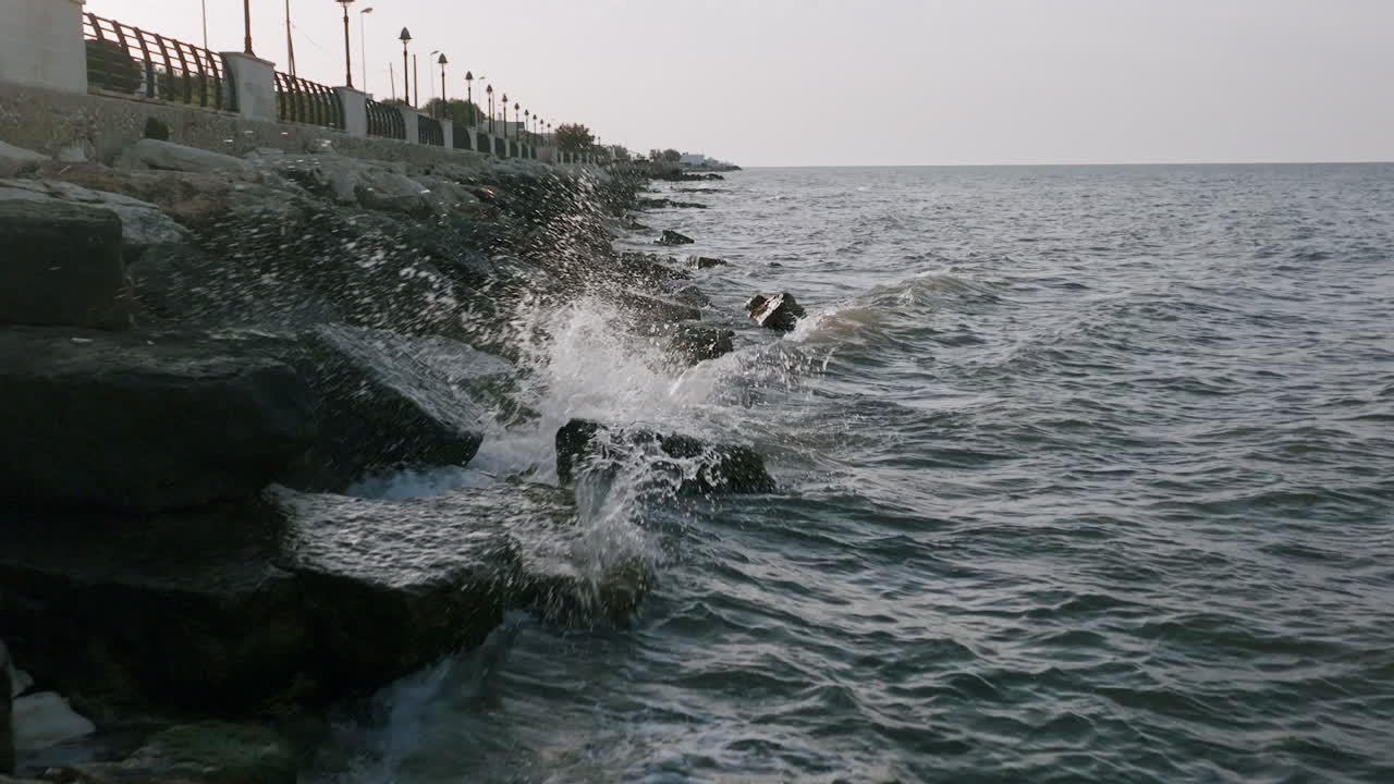 imágenes aéreas en cámara lenta de pequeñas olas rompiendo contra las rocas en bari, italia durante la puesta de sol
