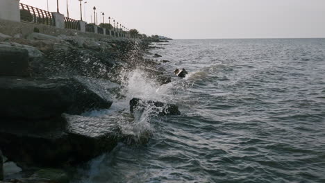 imágenes aéreas en cámara lenta de pequeñas olas rompiendo contra las rocas en bari, italia durante la puesta de sol