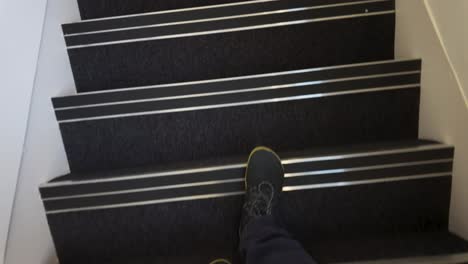 pov looking down at feet in blue shoes walking down stairs