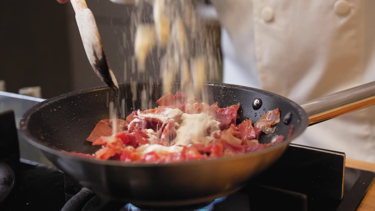 요리사는 팬에 밀가루로 햄을 뿌린다