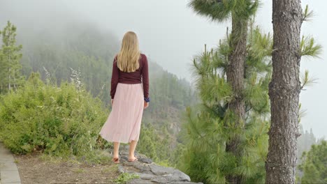 pretty woman walks along rocky overlook at top of mountain in teide national park