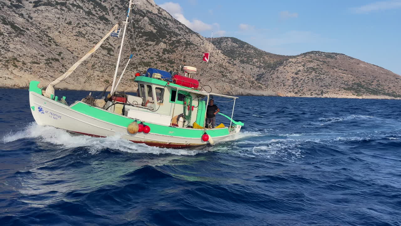 Greece,Kalimonos Island, somewhere in the Eagean Sea a fisherman in his traditional colorful fishing boat in motion on a sunny day.