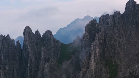 lombardy, italy - a captivating scene of fog-draped, jagged peaks rising from the rugged slopes of grignetta - pan up shot