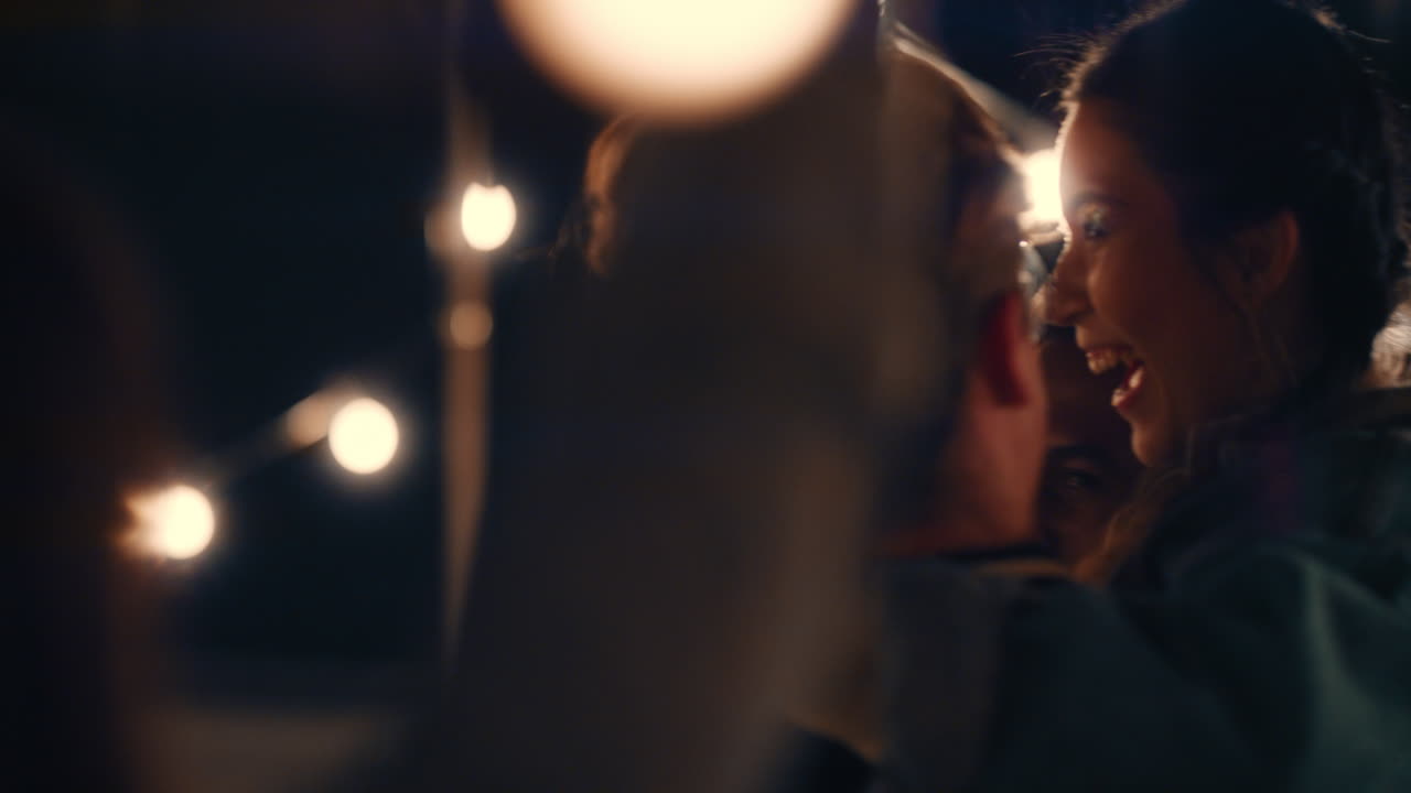 젊은 그룹 친구들이 즐겁게 놀이로 함께 춤을 추고 밤에 옥상 파티를 즐기고 웃으며 우정을 축하합니다.