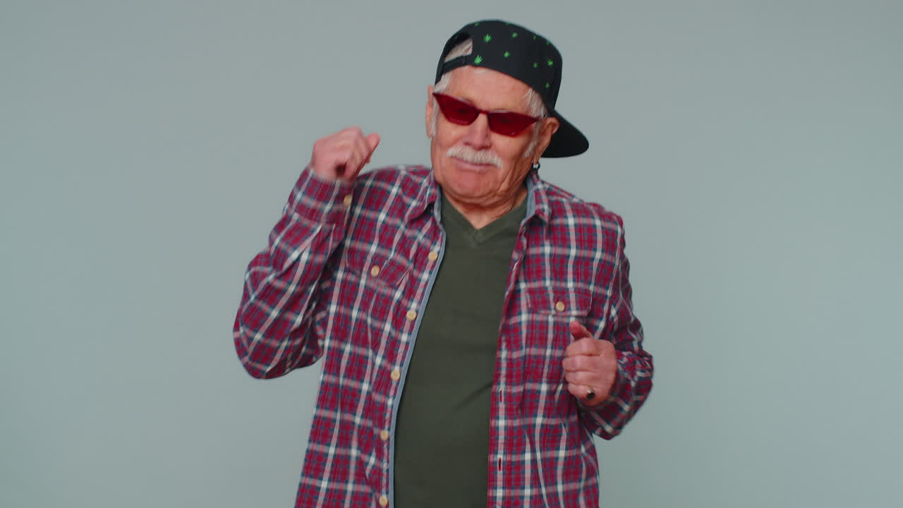Uomo divertente che ascolta musica, sorride e balla al ritmo di musica da discoteca, muovendo ritmicamente le mani e divertendosi.