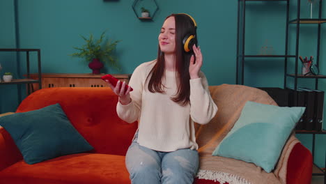 Una-Joven-Bastante-Caucásica-Con-Auriculares-Escuchando-Música-Bailando,-Cantando-En-El-Salón-De-Casa