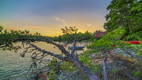 sunset motion time lapse of a coastline in near stockholm, sweden with a boat tied to a dock by a cottage
