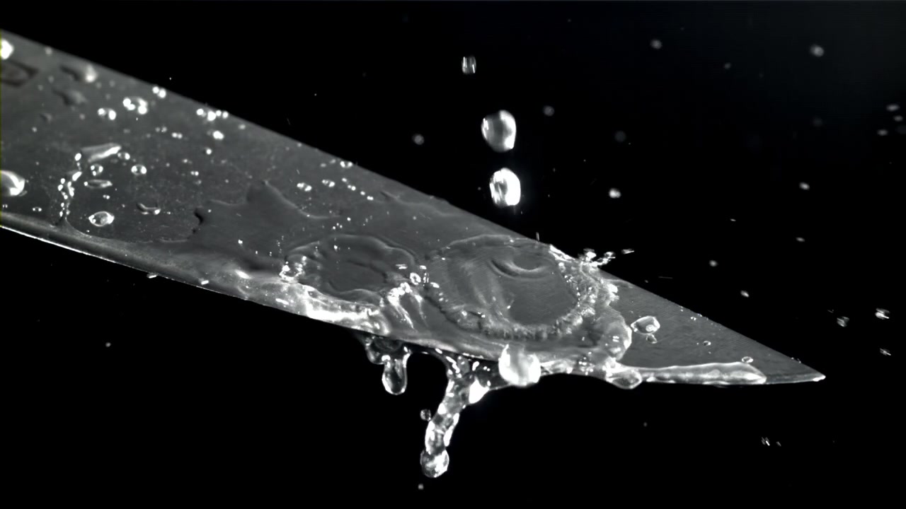 Gocce d'acqua che schizzano su una lama di coltello al rallentatore