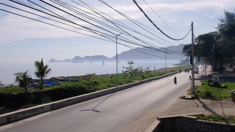 Busy-waterfront-road-with-traffic-commuting-at-rush-hour-in-the-capital-city-Dili,-Timor-Leste,-Southeast-Asia,-time-lapse-of-everyday-life,-cars,-scooters-and-trucks