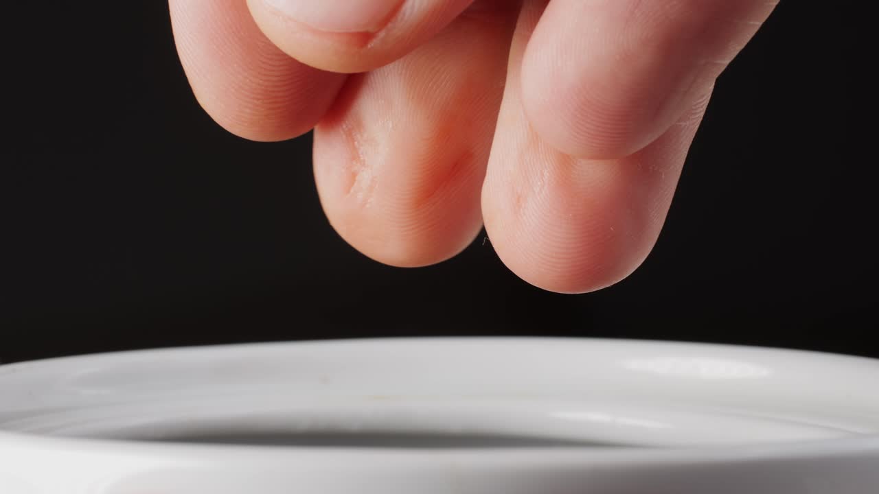 Hand pouring red spice into a white jar