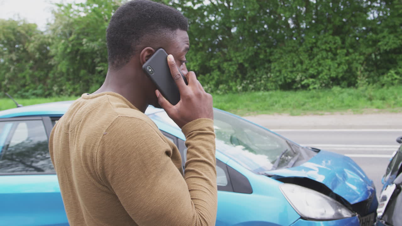 conductor masculino involucrado en un accidente automovilístico llamando a la compañía de seguros desde la carretera