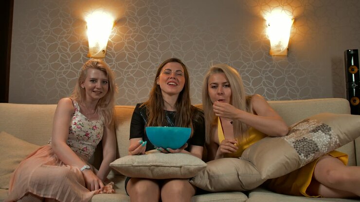 Tre belle ragazze giovani e sorridenti in abiti da sera guardano una commedia