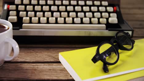 máquina de escribir antigua, diario, café negro y gafas en una mesa de madera 4k
