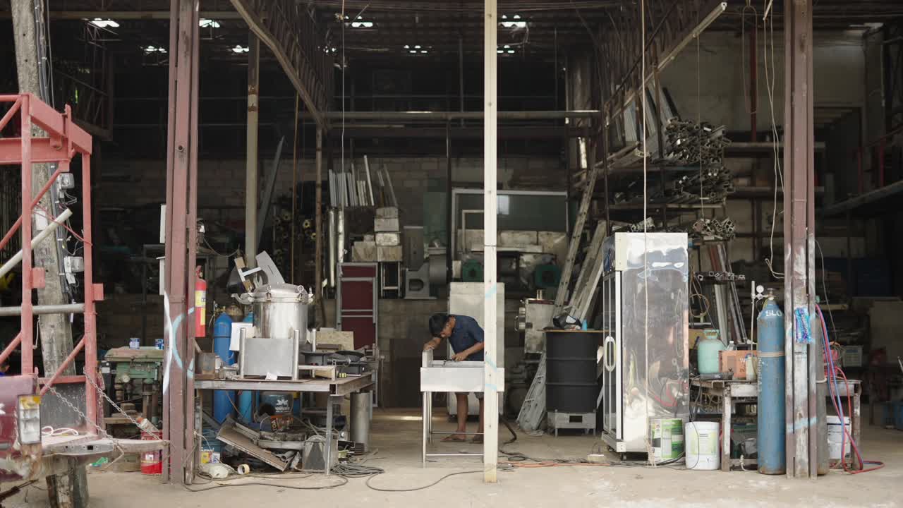 A man working in a cluttered metal fabrication workshop