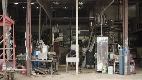 a man working in a cluttered metal fabrication workshop