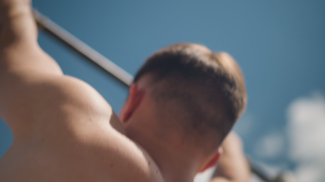 근육질의 남성이 야외에서 턱걸이 운동을 하고 있어요. 건장한 남성 운동선수가 길거리 헬스장에서 야외 턱걸이를 하고 있고, 백인 남성이 야외 헬스장에서 강도 높은 턱걸이 운동을 선보이고 있습니다.