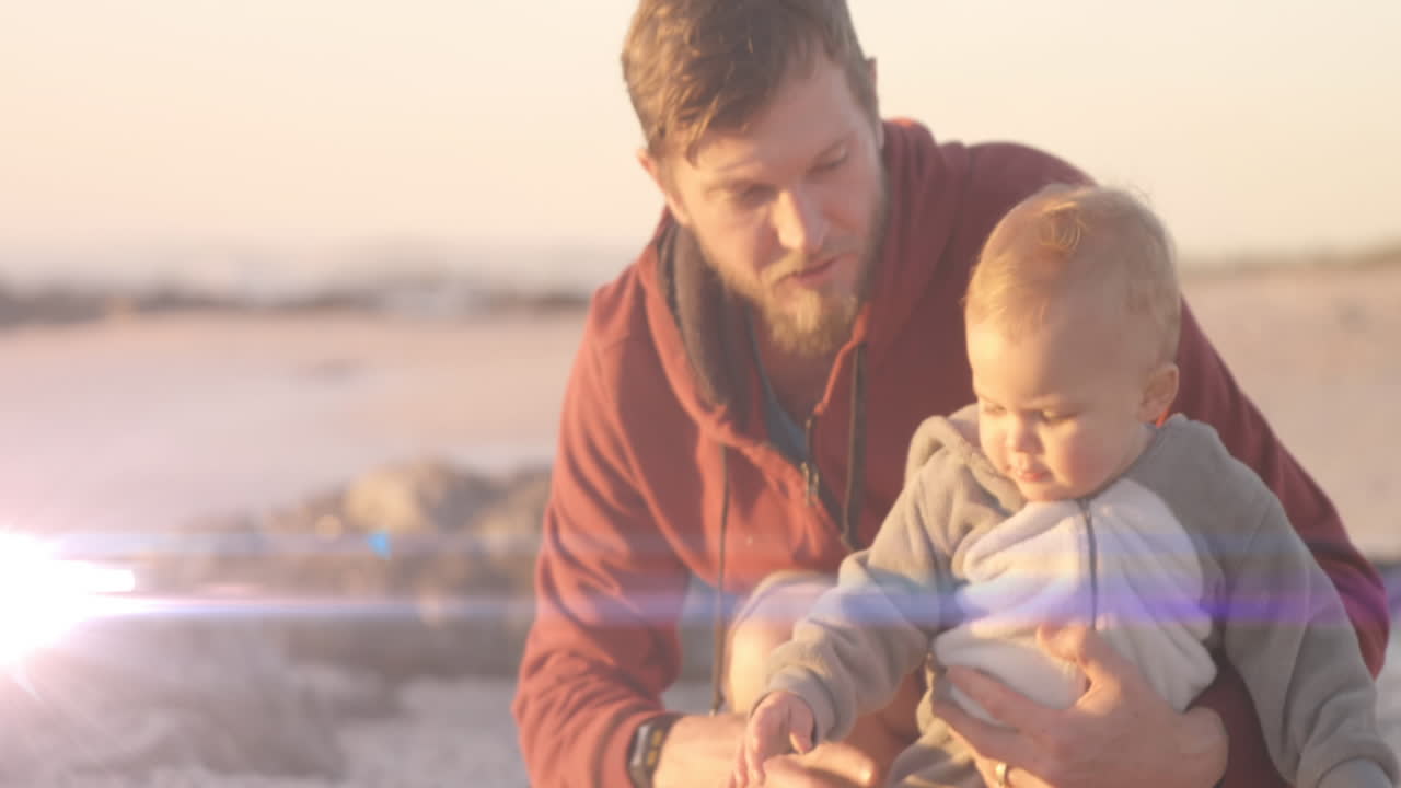 animación de puntos de luz sobre el padre caucásico sosteniendo a su hijo en la playa