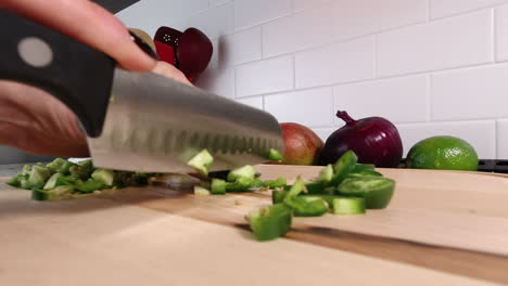 close up side angle of knife finely chopping spicy jalapenos