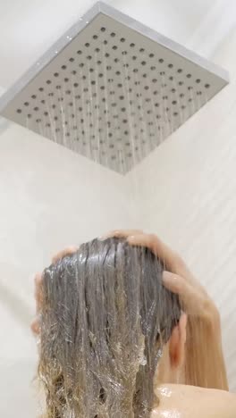 young woman washing hair in shower at home, back view. healthy lifestyle. beauty spa concept.