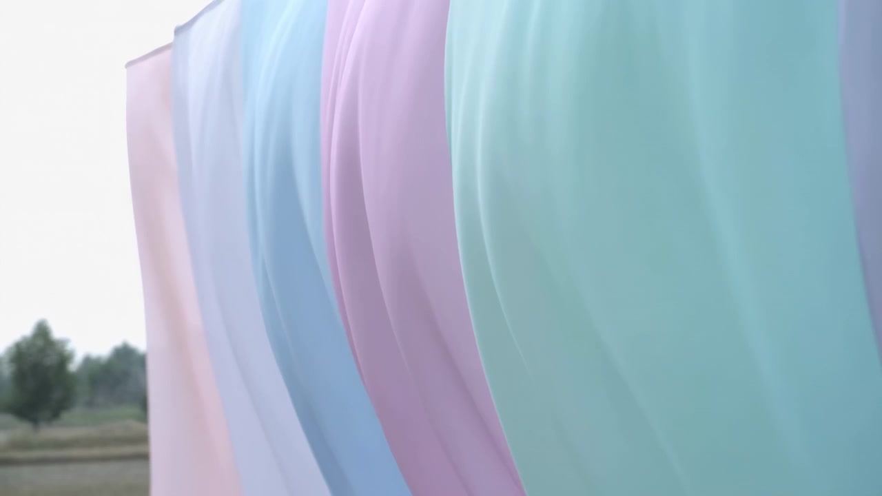 Multiple pastel textile panels in pink, blue, lavender, and aqua hang from rod, showing soft drape, subtle billow, blurred background, smooth folds, and airy minimal mood, with fabric, pastel, panel