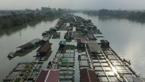 slow-drone-shot-flying-over-floating-fish-farming-community-in-Bien-Hoa-on-the-Dong-Nai-river,-Vietnam-on-a-sunny-day