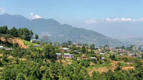 una vista de un pequeño pueblo en la cima de una colina con las montañas del himalaya en el fondo con una vista panorámica