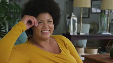 video of happy plus size african american woman sitting on sofa