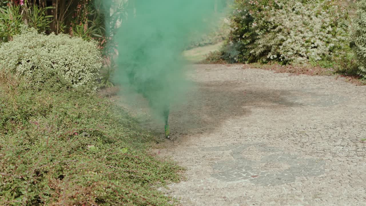 Nuvola di fumo verde che si alza da un bagliore su un sentiero di ghiaia in un giardino esterno