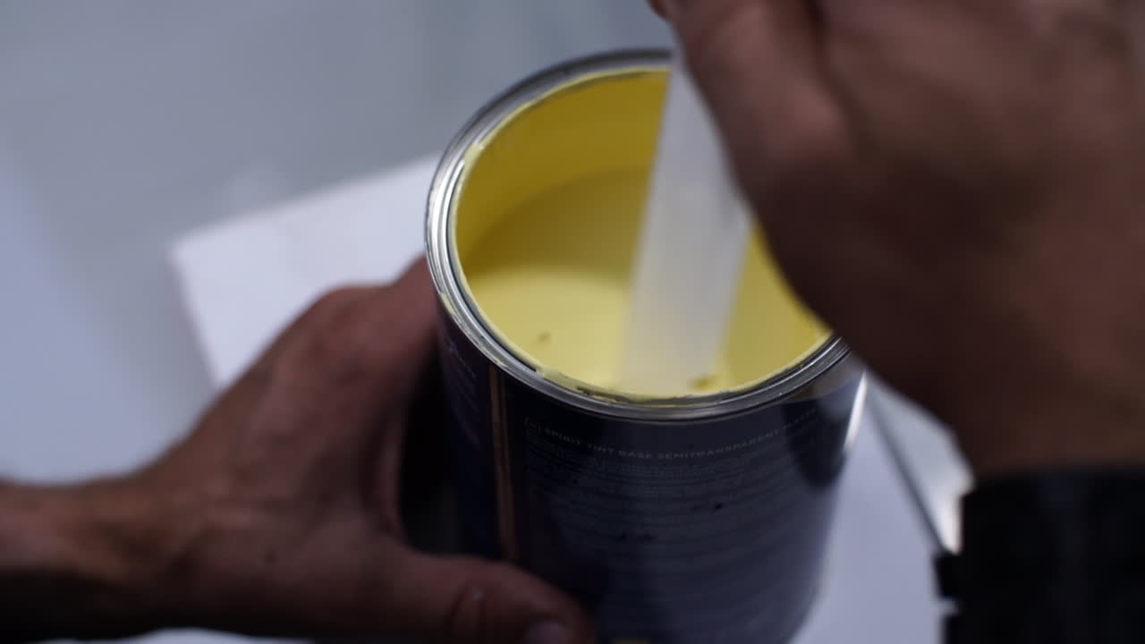 Professional painter stirring yellow paint