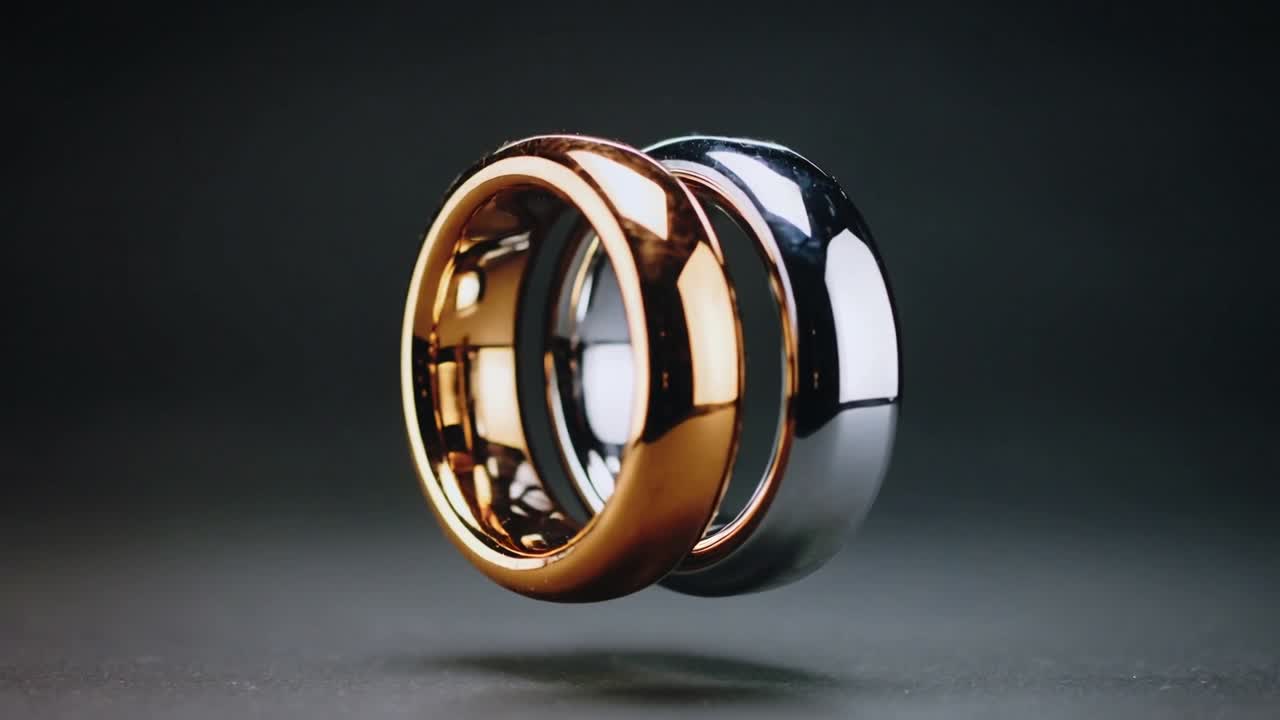 Floating rings splitting and rotating on playback in studio, revealing rose-gold and chrome bands