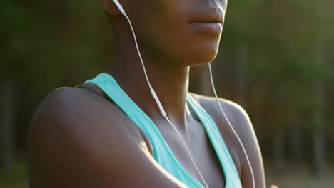 female athlete performing stretching exercise while listening music in forest 4k