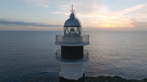 closeup shot of cap d'artrutx lighthouse at menorca balearic islands sea skyline background drone aerial rotating, sunset horizon