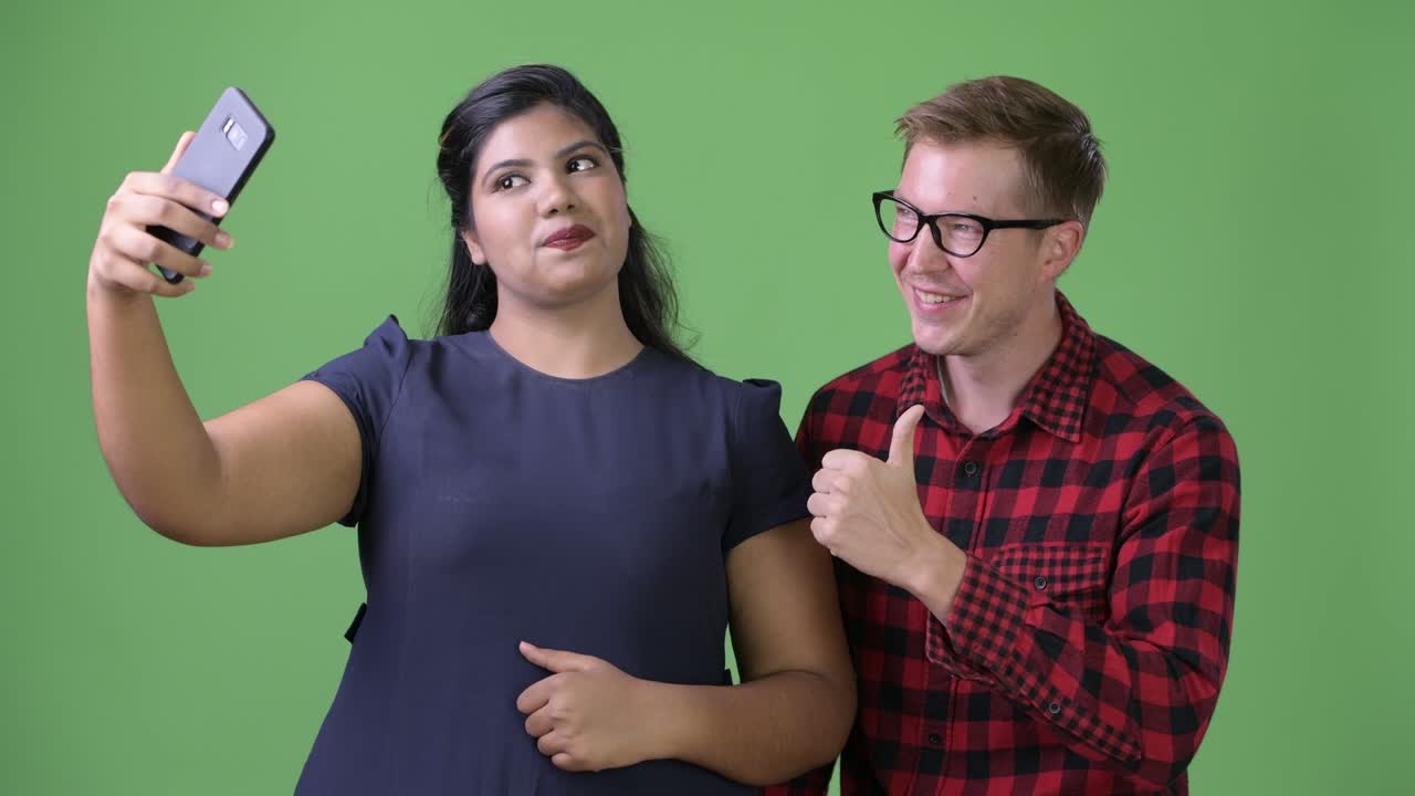 joven pareja de negocios multiétnica juntos contra un fondo verde